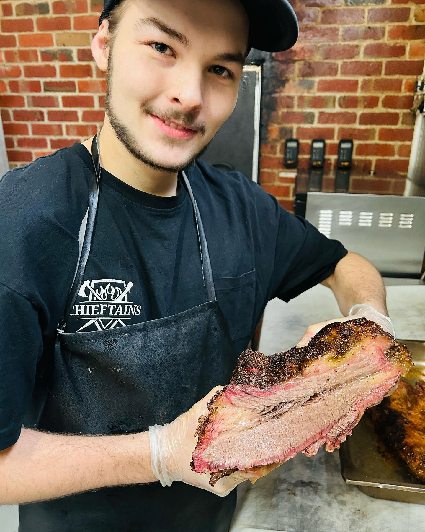 Chieftains pitmaster holding a perfectly smoked brisket with a deep bark and pink smoke ring